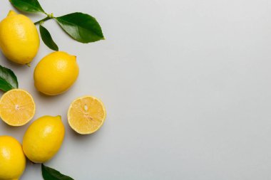 Renkli arka planda yeşil yapraklı taze limonlar, üst görünüm, metin için boşluk.