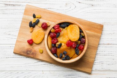 Masa arkasında farklı kurumuş meyveler olan bir kase, üst manzara. Kopyalama alanı olan sağlıklı yaşam biçimi.