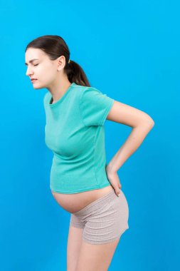 Sırtında ağrı olan hamile bir kadın, renkli arka planda izole edilmiş..