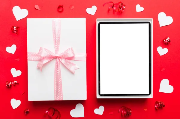 Gift box of open tablet for the holidays with a bow top view.