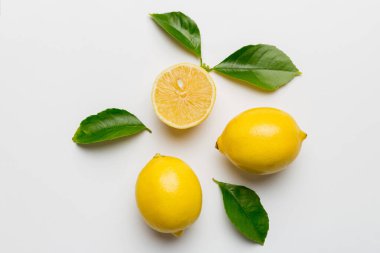 Renkli arka planda yeşil yapraklı taze limonlar, üst görünüm, metin için boşluk.