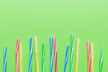 Renkli arka planda renkli plastik pipetler, düz yatış. Metin için Boşluğu Kopyala.