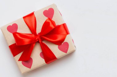 Top view photo of valentine day decorations gift box with red ribbon bow on colored background. Holiday gift boxes with top view.