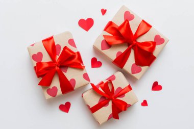 Top view photo of valentine day decorations gift box with red ribbon bow on colored background. Holiday gift boxes with top view.