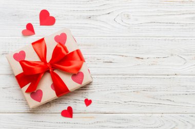 Top view photo of valentine day decorations gift box with red ribbon bow on colored background. Holiday gift boxes with top view.