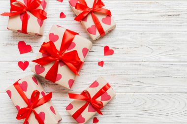 Top view photo of valentine day decorations gift box with red ribbon bow on colored background. Holiday gift boxes with top view.