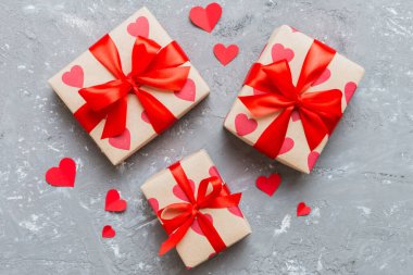 Top view photo of valentine day decorations gift box with red ribbon bow on colored background. Holiday gift boxes with top view.