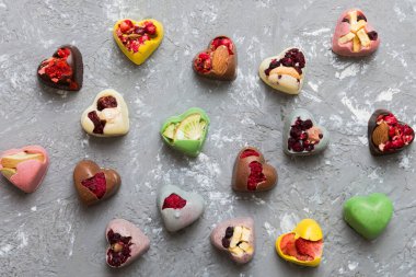 chocolate sweets in the form of a heart with fruits and nuts on a colored background. top view with space for text, holiday concept.