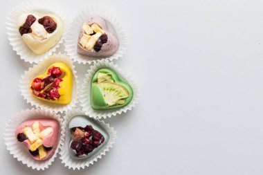 chocolate sweets in the form of a heart with fruits and nuts on a colored background. top view with space for text, holiday concept.
