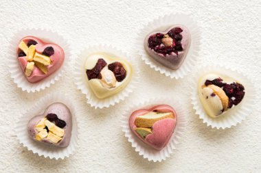 chocolate sweets in the form of a heart with fruits and nuts on a colored background. top view with space for text, holiday concept.