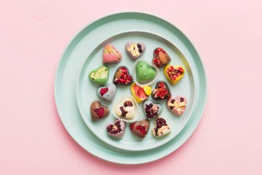 Plate with different chocolate on colored background. Assortment of fine chocolates top view vith copy space Health and obesity concept.