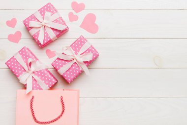 Gift boxes pop out from paper bag top view on colored background. bag packing handmade boxes fall out Concept of holidays, shopping, sale, discounts. Top view, flat lay.