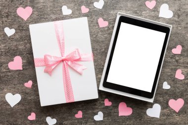 Gift box of open tablet for the holidays with a bow top view.