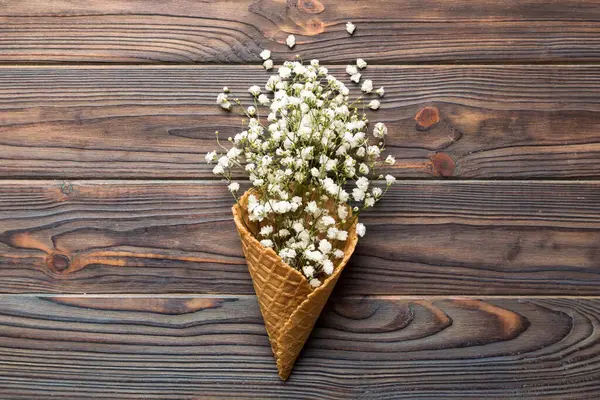 Waffle cone with beautiful gypsophila flowers on color background. summer concept. Copy space top view.