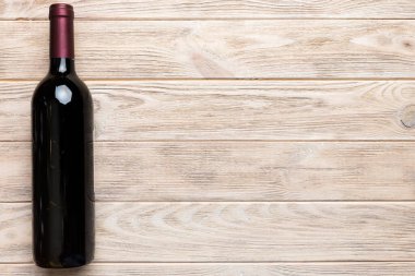 Renkli masada bir şişe kırmızı şarap. Düz konum, üst görünüm kopyalama alanı.