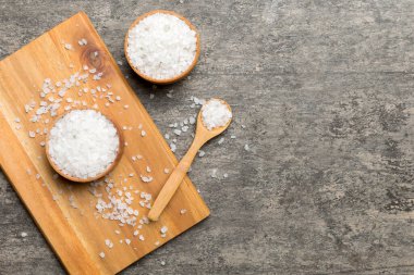 Ahşap bir arka planda ahşap bir kase tuz kristali. Kırsal kaselerdeki tuz, fotokopi alanı olan üst görünüm.