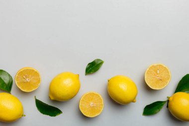 Renkli arka planda yeşil yapraklı taze limonlar, üst görünüm, metin için boşluk.