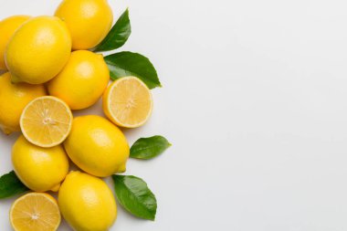 Renkli arka planda yeşil yapraklı taze limonlar, üst görünüm, metin için boşluk.