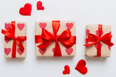 Top view photo of valentine day decorations gift box with red ribbon bow on colored background. Holiday gift boxes with top view.