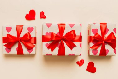 Top view photo of valentine day decorations gift box with red ribbon bow on colored background. Holiday gift boxes with top view.