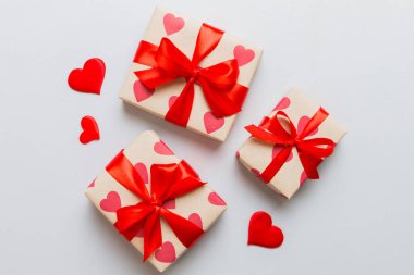 Top view photo of valentine day decorations gift box with red ribbon bow on colored background. Holiday gift boxes with top view.
