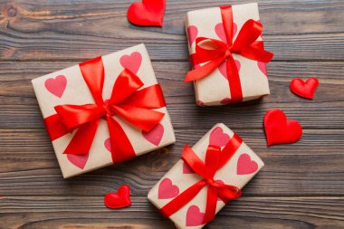 Top view photo of valentine day decorations gift box with red ribbon bow on colored background. Holiday gift boxes with top view.