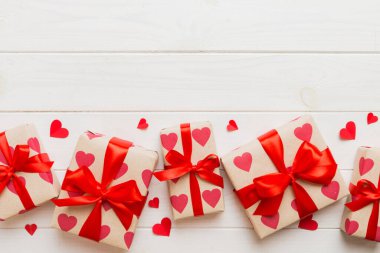 Top view photo of valentine day decorations gift box with red ribbon bow on colored background. Holiday gift boxes with top view.