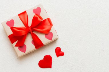 Top view photo of valentine day decorations gift box with red ribbon bow on colored background. Holiday gift boxes with top view.