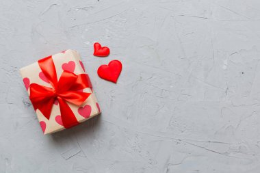 Top view photo of valentine day decorations gift box with red ribbon bow on colored background. Holiday gift boxes with top view.