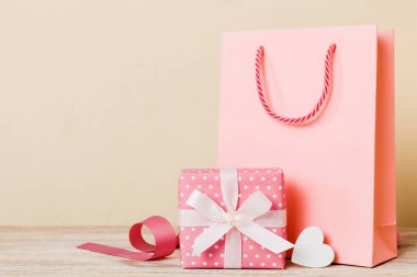 Shopping bag with gift box on colored background perspecrive view. Space for text holiday concept.