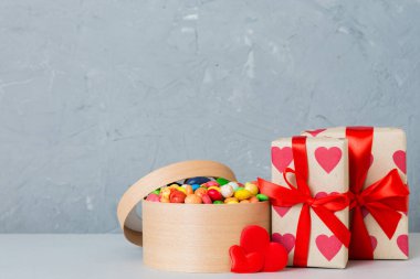 Valentine day composition: sweet candy, with gift boxes with bow and red felt hearts, photo template, background. Perspective with copy space.