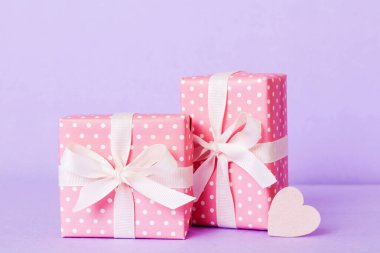 gift box with red bow and red heart on colored background. Perspective view. Flat lay.