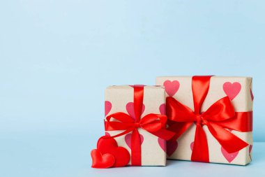 gift box with red bow and red heart on colored background. Perspective view. Flat lay.