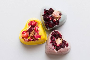 chocolate sweets in the form of a heart with fruits and nuts on a colored background. top view with space for text, holiday concept.
