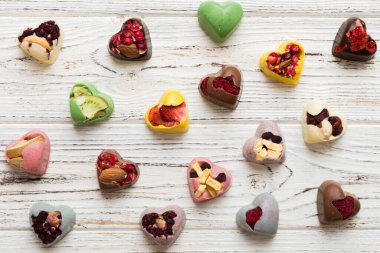 chocolate sweets in the form of a heart with fruits and nuts on a colored background. top view with space for text, holiday concept.