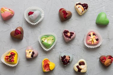 chocolate sweets in the form of a heart with fruits and nuts on a colored background. top view with space for text, holiday concept.