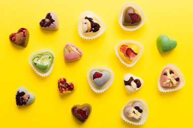 chocolate sweets in the form of a heart with fruits and nuts on a colored background. top view with space for text, holiday concept.