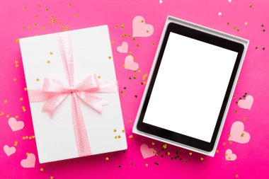 Gift box of open tablet for the holidays with a bow top view.