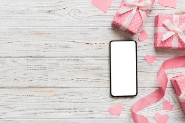 mobile phone with blank screen on colored background with hearts, valentine day concept top view flat lay.