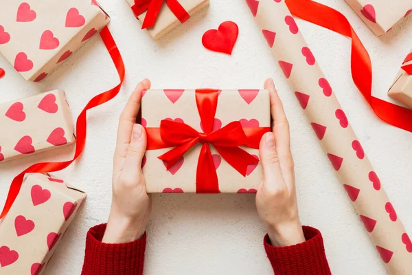 Give a gift on Valentine Day.Valentine gift. Beauty Woman hands holding Gift box with red bow over holiday background.