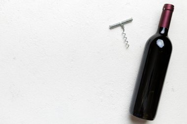 Renkli masada tirbuşonlu bir şişe kırmızı şarap. Düz konum, üst görünüm kopyalama alanı.