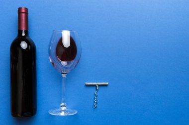 Tirbuşonlu düz kompozisyon, bir şişe şarap ve renkli masada zarif bir cam. Düz konum, üst görünüm kopyalama alanı.