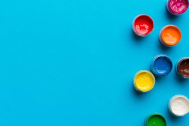 Renkli arka planda farklı renkte gagalı kavanozlar. Hobi resim. Boşluğu olan üst görünüm. Yaratıcılık için işyeri. ev öğretmenliği kavramı çizimi.