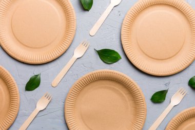 Açık beyaz masa arkaplanındaki boş, tek kullanımlık çevre dostu tabaklar, bardaklar, çatal bıçaklar. Üst Manzara. Biyo-çözünebilir el yapımı yemekler. Geri dönüşüm konsepti. Yakın plan..