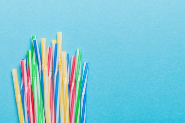Renkli arka planda renkli plastik pipetler, düz yatış. Metin için Boşluğu Kopyala.