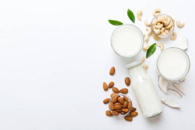 Masa arkasında çeşitli vejetaryen süt bademi, hindistan cevizi, fındık. Vejetaryen bitkisi sütü ve malzemeleri, üst görünüm.