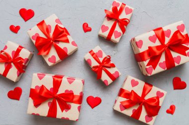 Top view photo of valentine day decorations gift box with red ribbon bow on colored background. Holiday gift boxes with top view.