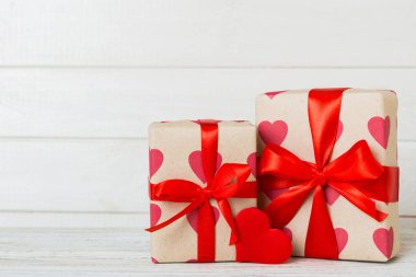gift box with red bow and red heart on colored background. Perspective view. Flat lay.