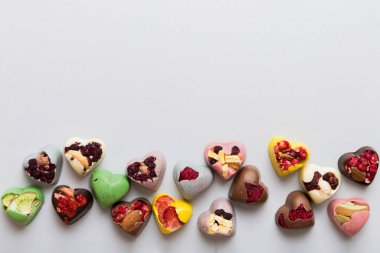 chocolate sweets in the form of a heart with fruits and nuts on a colored background. top view with space for text, holiday concept.