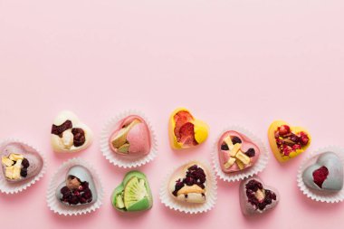 chocolate sweets in the form of a heart with fruits and nuts on a colored background. top view with space for text, holiday concept.
